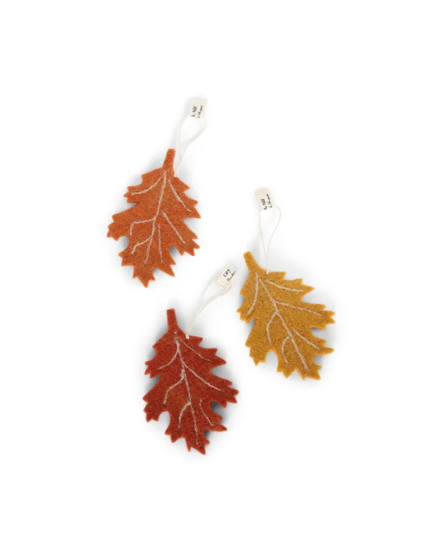 Drei herbstliche Filzanhänger in Birkenblatt-Form von Gry & Sif in Currygelb, Orange und Dunkelorange vor weißem Hintergund.