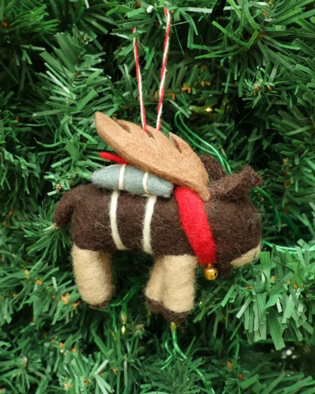 Dekorierter Elch Weihnachts-Filzanhänger "Elton" von Grace & Gloria. hängt am Tannenbaum. Der Elch hat Flügel und trägt eine Glocke um sein Hals.