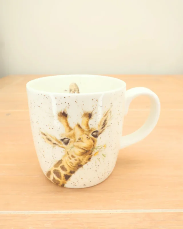 Große Giraffen-Tasse „Lofty“ auf hellem Holztisch, Detailaufnahme des Giraffenmotivs.