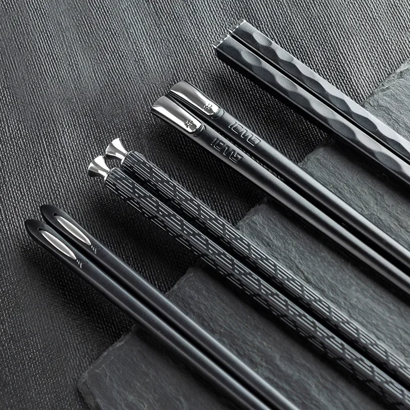 Moderne schwarze Essstäbchen aus Metall auf Schiefer, Küchenutensilien für stilvolles Kochen