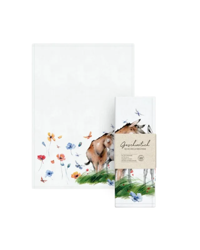 Geschirrtuch „Kuschelfreunde“ vom Grätz Verlag zusammen mit der Verpackung. Das Motiv zeigt zwei sich zärtlich anlehnende Esel, die von einer bunten Sommerwiese mit Blumen und Schmetterlingen umgeben sind.