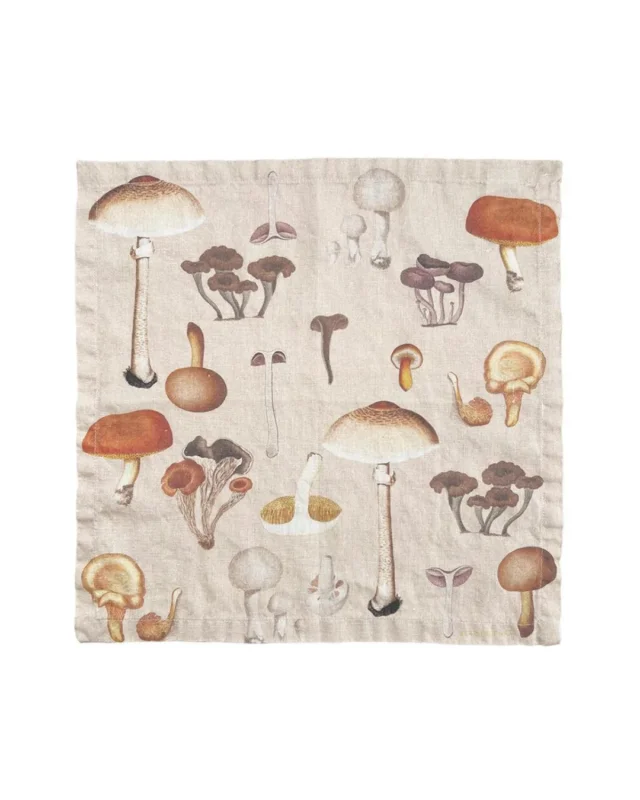 Pilz Leinen Stoffserviette "Mushroom" von Koustrup & CO vor weißen Hintergrund. Die Serviette ist Beige mit vielen verschiedenen Pilzen als Motiv.